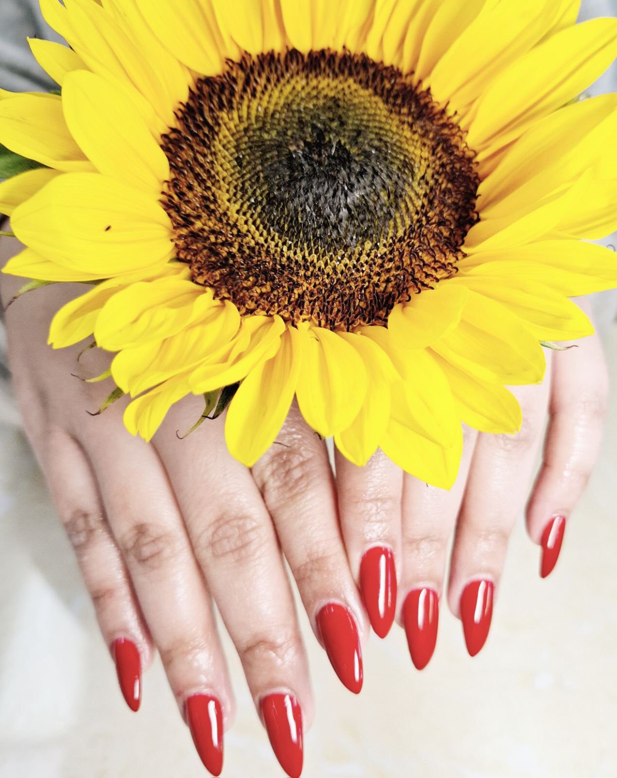 A set of glossy red almond nails, photographed at the salon